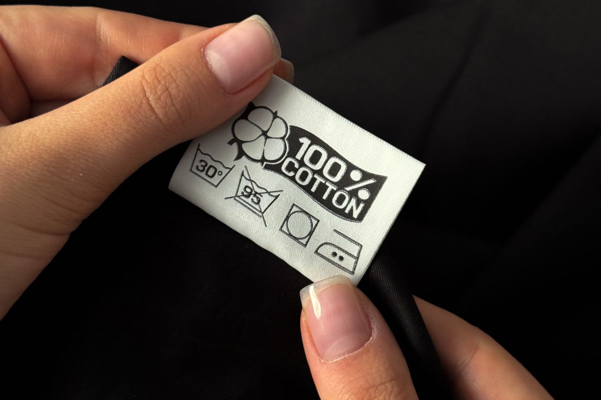 Hands holding a clothing composition label